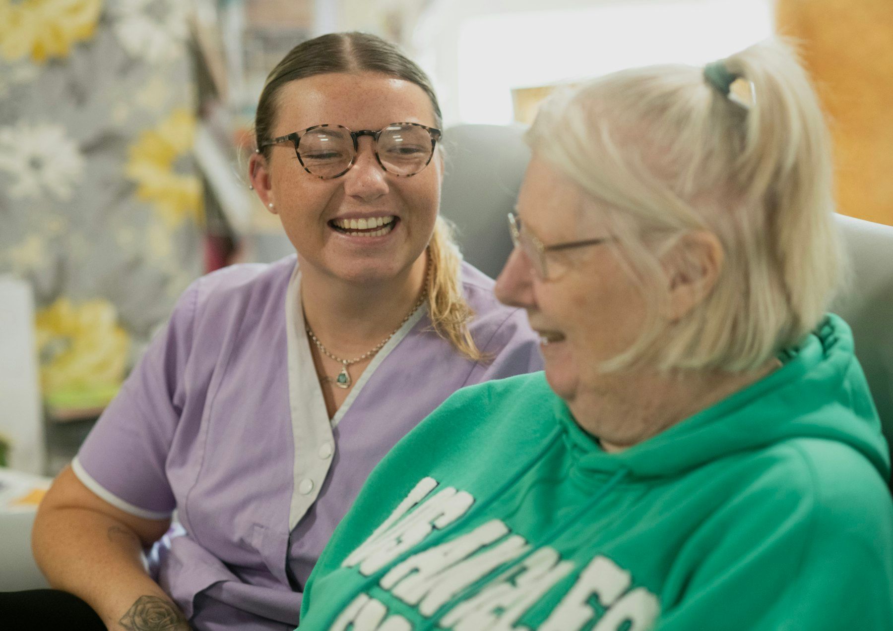 A nurse and an older woman laugh together